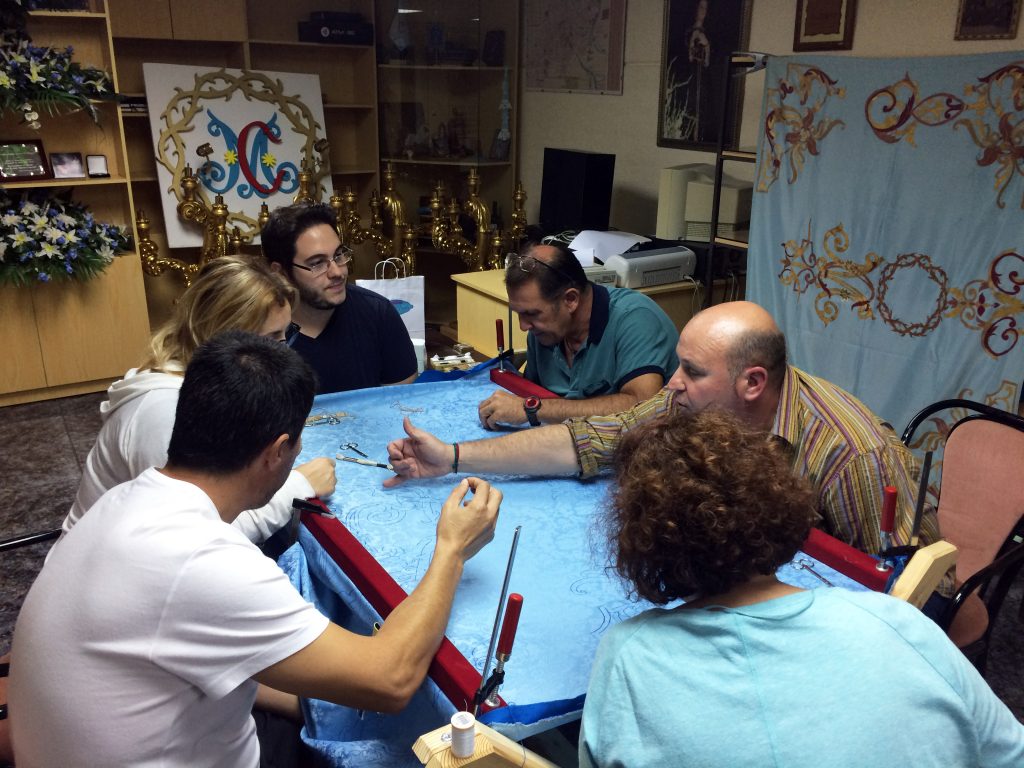Los primeros miembros del taller de bordado atendiendo algunas explicaciones para proceder con el bordado de la bandera.